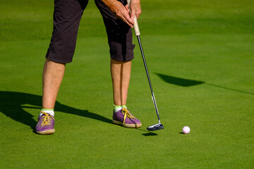 close up of feet of female senior golfer putting on green