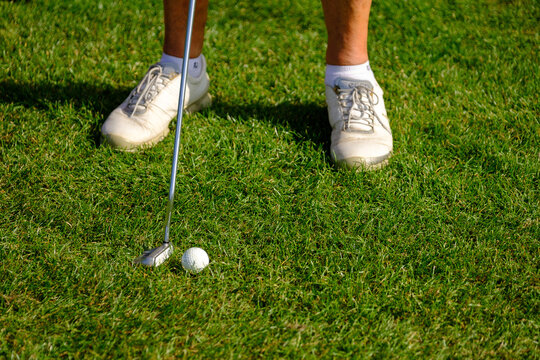 close up of feet of female senior golfer putting on rough