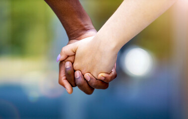 Interracial couple holding hands outdoors
