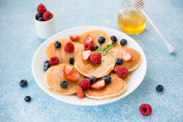 Morning pancakes with honey and berries in a plate