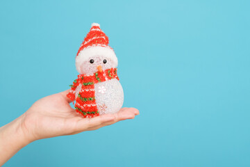 snowman in hand of woman,  Christmas toy in a female hand on blue background