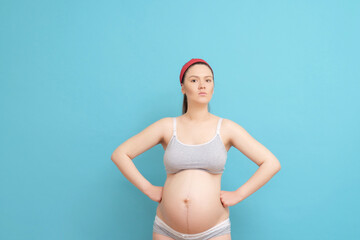 serious young pregnant woman on blue background