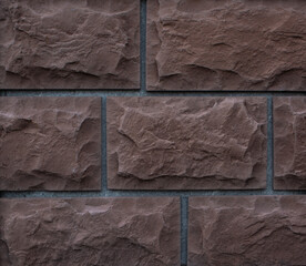 texture of brown rough textured blocks of the building facade; decorative background for design