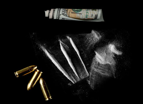 Cocaine line, bullets gun and hundred dollar roll isolated on black background 