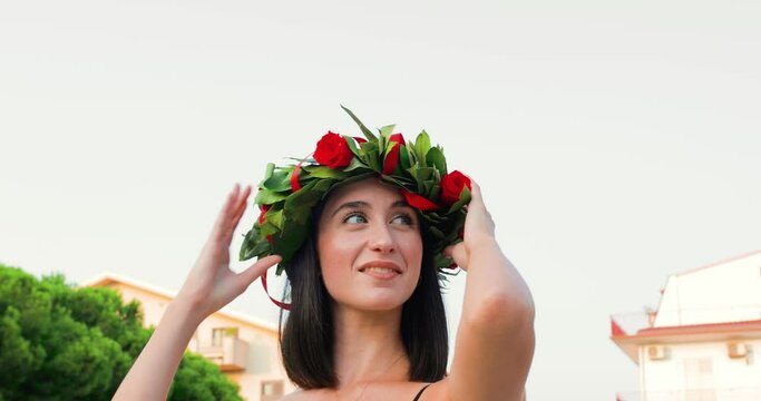 Giovane ragazza laureata con corona di alloro in testa sorride felice