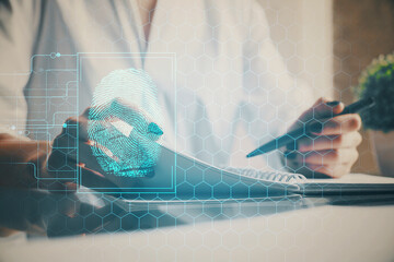 Blue fingerprint hologram over hands taking notes background. Concept of security. Double exposure