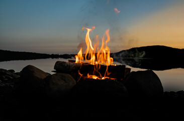 Cozy camp fire on the beach of a lake in the evening.