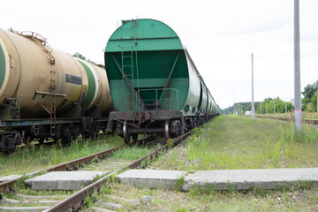 Fototapeta na wymiar Two trains with carriages stand on the railway crossing. Cargo wagons and tank cars on the rails close-up