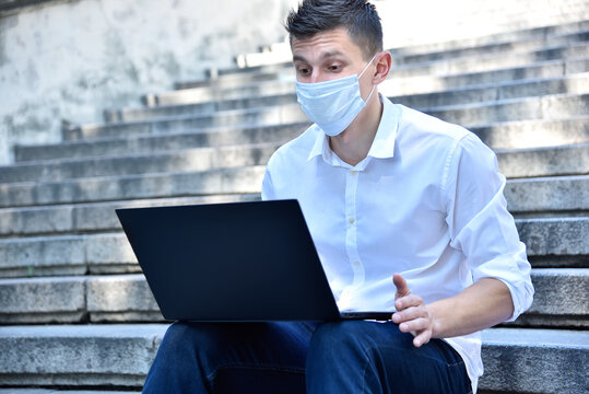Businessman in mask typing on laptop keyboard.