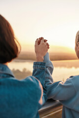 Two girls holding hands while watching the sunrise together, Young lesbian couple having romantic moment outdoors