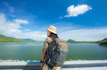 Obraz premium Stylish hipster girl in hat walking on top of mountains. Happy young woman with backpack exploring sunny mountains. Travel and wanderlust concept. Amazing atmospheric moment 