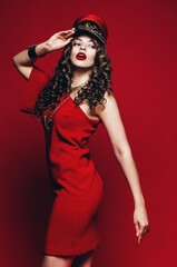 woman posing in red dress and holding hat