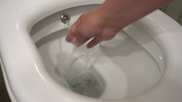 Closeup view of white toilet bowl and bidet water spray