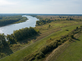 Naklejka premium Dirt road among green meadows. Summer sunny day. Aerial drone view.