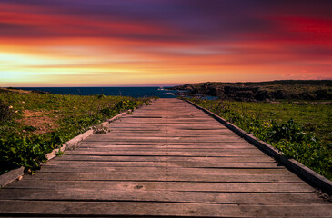 Obraz na płótnie Canvas wooden footbridge to the sea at sunset