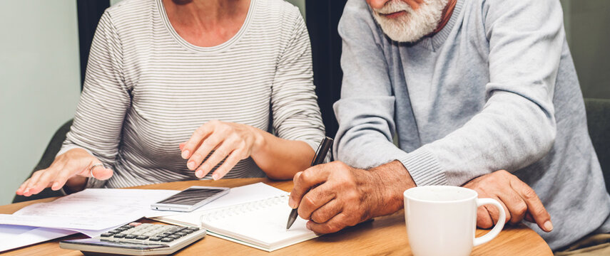 Senior Couple Reading Documents And Calculating Bills To Pay In Living Room At Home.Retirement Couple And Loan Bankruptcy Money Concept