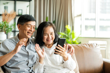 Happy senior old asian lover couple holding smartphone looking at cellphone screen laughing casual...