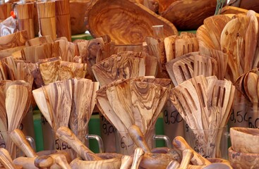 Close up view on wooden dinner sets consist from forks, spoons,  dishes, bowls, dippers and ladles on a local market in Freiburg im Breisgau at Cathedral Market. 