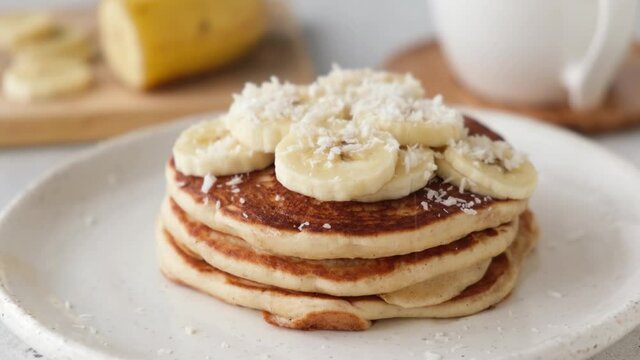 Pancakes with banana and coconut flakes. Decorating pancakes with coconut flakes