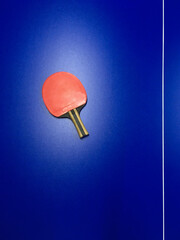 old, red, shabby table tennis racket on a blue table