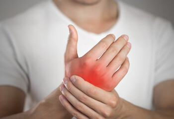 Pain in the hand of a man. Highlighted in red. On a gray background. Close up