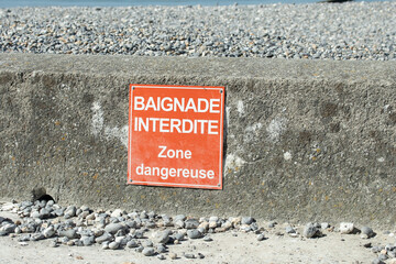panneau sur une plage avec écrit dessus "baignade interdit, zone dangereuse"