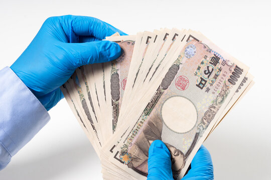 Man's Hands In Blue Nitrile Glove Holding Bank Notes