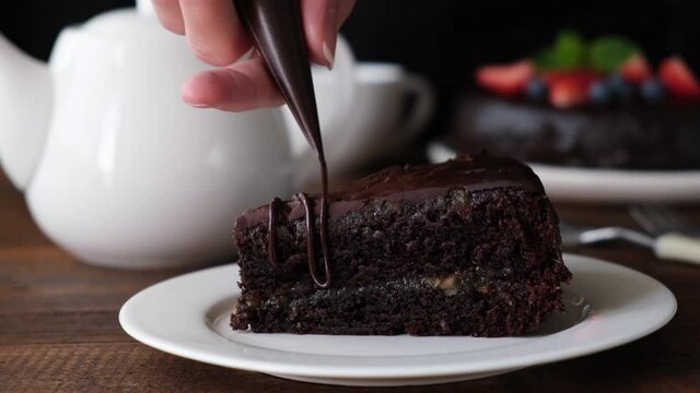 Pastry chef decorating chocolate cake with chocolate icing. Zacher or cake, deep dark moist chocolate cake