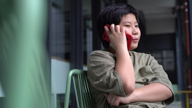 Asian Boy talk and listen to a phone in a cafe corridor