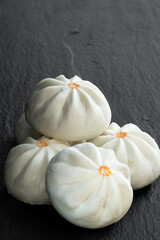 Steamed bao buns with delicious filling on black stone background