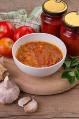 Bol con salsa de tomate casera, tarros de conserva e ingredientes