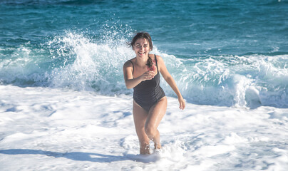 Cheerful woman in a bathing suit runs by the sea