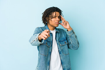 Young black man wearing a jeans jacket pointing temple with finger, thinking, focused on a task.