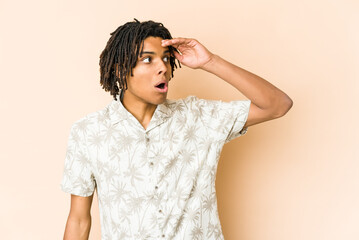 Naklejka premium Young african american rasta man looking far away keeping hand on forehead.