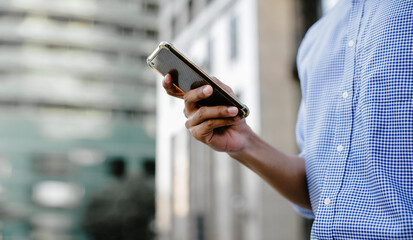 a Businessman Using Mobile Phone in the City. Cropped image, selective focus on Smartphone