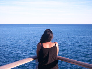 Afro-Asian woman seen from behind looking at the sea