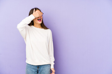 Young caucasian woman isolated on purple background covers eyes with hands, smiles broadly waiting for a surprise.