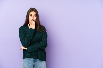 Young caucasian woman isolated on purple background yawning showing a tired gesture covering mouth with hand.