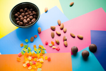 almonds and dried fruits on a colored background next to a plate with hazelnuts