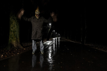 Scary Halloween angry corn in dark forest. Horror concept. Creepy man in mask of maize standing on the dark road in park. Fear and Halloween theme