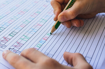 Buchstaben schreiben üben beim Schul Hausaufgaben machen zu Hause. Ein grüner Buntstift schreibt...