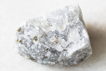 closeup of sample of natural mineral from geological collection - unpolished Melilitolite rock on white marble background
