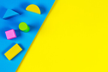 Wooden colorful blocks on geometric yellow and blue background. Top view, flat lay