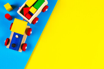 Baby kid toys background. Wooden toy train with colorful blocks on light blue and yellow background. Top view