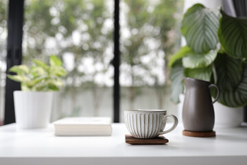 Vintage clay cup with pot and book and plant pot on white table 