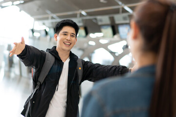 Asian happy and smile man running open arms to embrace friend or girlfriend at arrival gate in airport terminal. welcome back home from study or working abroad. 