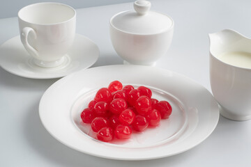 white porcelain tea set with popping out red cherries on big plate in front