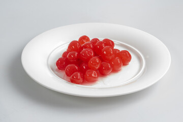 white plate with red sweet cherries on white background