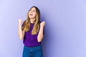 Fototapeta na wymiar Young caucasian woman isolated on purple background raising fist after a victory, winner concept.