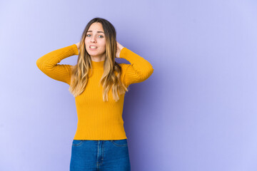 Young caucasian woman isolated on purple background touching back of head, thinking and making a...